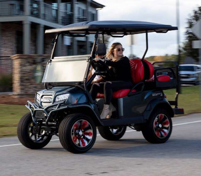 Lifted grey golf cart with red custom seats driving in neighborhood