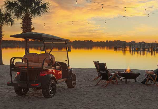 Red lifted golf cart beach scene with fire pit